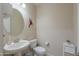 Charming powder room featuring a pedestal sink and round mirror at 40725 W Hall Dr, Maricopa, AZ 85138