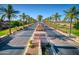 Street view of The Lakes at Rancho El Dorado, lined with palm trees and lush landscaping at 40725 W Hall Dr, Maricopa, AZ 85138