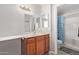 Traditional bathroom with a wood vanity, framed mirrors, and a shower with blue curtain at 4629 N 78Th Dr, Phoenix, AZ 85033