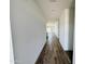 Long hallway with wood-look flooring and white walls leading to a bright and open living area at 46819 W Cansados Rd, Maricopa, AZ 85139