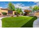 Landscaped backyard oasis featuring a putting green, porch swing, and lush plants, perfect for outdoor enjoyment at 5910 W Blue Sky Dr, Phoenix, AZ 85083