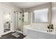 A well-lit bathroom featuring a glass shower and soaking tub next to the window at 5910 W Blue Sky Dr, Phoenix, AZ 85083