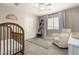 Bedroom with wood crib, shelves, accent rug, white armchair, and window with blinds at 5910 W Blue Sky Dr, Phoenix, AZ 85083