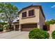 Exterior view of a two story home with a three car garage, desert landscaping and mature trees at 5910 W Blue Sky Dr, Phoenix, AZ 85083