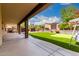The large covered patio overlooks the manicured yard with putting green, porch swing, and lush landscape at 5910 W Blue Sky Dr, Phoenix, AZ 85083