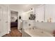 Bright bathroom featuring a soaking tub, white cabinets, and a doorway to the main bedroom at 654 W Fremont Dr, Tempe, AZ 85282