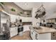 Charming kitchen boasts white cabinets, stainless appliances, tan countertops, and hanging pot rack above the island at 654 W Fremont Dr, Tempe, AZ 85282