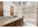 Bathroom with a vanity with granite countertop, travertine style tile, and a tub with matching tile surround at 7018 E Ingram St, Mesa, AZ 85207
