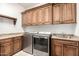 Bright laundry room with stainless steel washer and dryer, custom wood cabinets, and stone countertops at 7018 E Ingram St, Mesa, AZ 85207