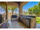 Entertain in this covered outdoor kitchen featuring stainless steel appliances and ample counter space at 7018 E Ingram St, Mesa, AZ 85207