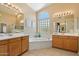 Bright main bathroom featuring dual vanities, a soaking tub, and a glass block window at 7438 E Glenn Moore Rd, Scottsdale, AZ 85255