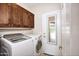 Convenient laundry room features modern washer and dryer, wooden cabinets, and a mirror on the exit door at 8228 S Stephanie Ln, Tempe, AZ 85284