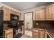 Kitchen features wooden cabinets, black appliances, tile floors, and views to the laundry room at 1110 E Utopia Rd, Phoenix, AZ 85024