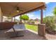 Covered patio with hammock overlooking green grass, fence and landscaping in this backyard view at 11411 W Dana Ln, Avondale, AZ 85392