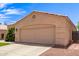 Beige home showing attached two car garage and a meticulously manicured lawn at 11411 W Dana Ln, Avondale, AZ 85392