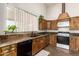 Sunlit kitchen featuring a stainless steel dishwasher, oven, and wooden cabinets at 11411 W Dana Ln, Avondale, AZ 85392