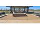 Community picnic area with tables under a shaded structure, with a fire pit, landscaping, and benches at 15792 W Beryl Ave, Waddell, AZ 85355