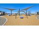 Community playground featuring swings and a slide beneath sun-shade canopies on a wood chip base at 15792 W Beryl Ave, Waddell, AZ 85355