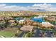 Expansive aerial view of a community with a lake, clubhouse, tennis courts, and scenic mountain backdrop at 21150 N Evergreen Dr, Maricopa, AZ 85138
