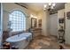 Bright bathroom features a freestanding tub with glass block window and decorative chandelier, offering a spa-like retreat at 2160 E Kenwood St, Mesa, AZ 85213