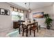 Cozy dining room featuring a rustic wooden table and bench, a modern chandelier, and a view of the front yard at 2229 N 139Th Dr, Goodyear, AZ 85395