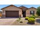 Charming single-story home featuring a stone-accented entrance, desert landscaping, and a brick paver driveway at 2229 N 139Th Dr, Goodyear, AZ 85395