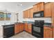 Well lit kitchen featuring wood cabinetry, granite countertops, and black appliances at 2337 E Fraktur Rd, Phoenix, AZ 85040