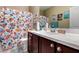 Bright bathroom featuring a spacious vanity, white sink, dark wood cabinets, and a modern shower curtain at 23707 W Hess Ave, Buckeye, AZ 85326