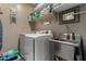 Efficient laundry room with a stainless steel utility sink, shelving, and a modern washer and dryer at 23707 W Hess Ave, Buckeye, AZ 85326