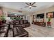 Cozy living room with tile floors, ceiling fan, and brown leather sofa adjacent to the kitchen at 23707 W Hess Ave, Buckeye, AZ 85326