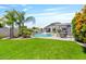 Well-maintained backyard with lush green lawn, tropical palm trees, and a shimmering pool at 25421 S 228Th St, Queen Creek, AZ 85142