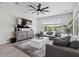 Bright living room with a ceiling fan, large windows, and a comfortable gray sectional sofa at 25421 S 228Th St, Queen Creek, AZ 85142