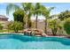 Lush backyard pool area with tropical landscaping, a rock waterfall feature, and clear blue water at 25421 S 228Th St, Queen Creek, AZ 85142
