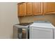Modern laundry room showcasing a front-load washer and dryer with wood cabinets above at 3152 E San Pedro Ct, Gilbert, AZ 85234