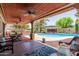 Charming covered patio with a ceiling fans overlooks a pool, providing an ideal space for relaxation and dining at 3377 W Grandview Rd, Phoenix, AZ 85053