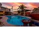 Sparkling backyard pool with a rock waterfall feature, surrounded by lush landscaping and a covered patio at 3377 W Grandview Rd, Phoenix, AZ 85053