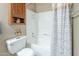 Neutral bathroom featuring white tub and shower, decorative butterfly accent, and wood storage cabinet at 3830 E Lakewood Pkwy # 1051, Phoenix, AZ 85048