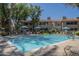 Community swimming pool with blue umbrellas, lounge chairs, and a glimpse of the building in the background at 3830 E Lakewood Pkwy # 1051, Phoenix, AZ 85048