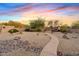 Desert landscaped backyard with stone accents, outdoor seating area and mature trees at 4111 N Starry Pass Cir, Mesa, AZ 85207