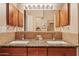 Bathroom vanity featuring double sinks, wooden cabinets, granite countertop, and decorative lighting at 4111 N Starry Pass Cir, Mesa, AZ 85207
