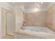 Bathroom featuring travertine tile walls, a whirlpool tub and a glass enclosed shower at 6550 N 7Th St, Phoenix, AZ 85014
