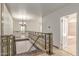 Elegant hallway with decorative railing overlooking stairs, tiled floor, and doorway to bathroom at 6550 N 7Th St, Phoenix, AZ 85014