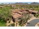 An aerial view of a desert home showcasing its unique architecture, surrounded by lush landscaping and mountain views at 8974 E Rusty Spur Pl, Scottsdale, AZ 85255