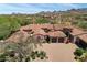 Stunning aerial view of an estate home with a tile roof, paver driveway, manicured landscape and mountain backdrop at 8974 E Rusty Spur Pl, Scottsdale, AZ 85255