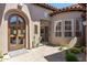 Inviting front entrance features a wooden door, a stone courtyard and lush desert landscaping at 8974 E Rusty Spur Pl, Scottsdale, AZ 85255