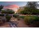 Serene backyard with manicured landscaping, stone pathway, and ambient lighting at dusk at 9035 W Villa Chula --, Peoria, AZ 85383