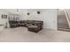 Spacious living room with a large, worn leather sectional, carpet, and stairs leading to the second floor at 9035 W Villa Chula --, Peoria, AZ 85383