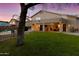 Spacious backyard with a covered patio, beautiful lawn, mature trees, and a glimpse of the pool at 9517 E Minton St, Mesa, AZ 85207