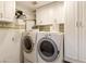 Convenient laundry room with white cabinetry, washer, and dryer machines at 9517 E Minton St, Mesa, AZ 85207