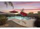 Resort-style pool featuring rock accents, waterfall, and lush tropical landscaping at twilight at 9517 E Minton St, Mesa, AZ 85207